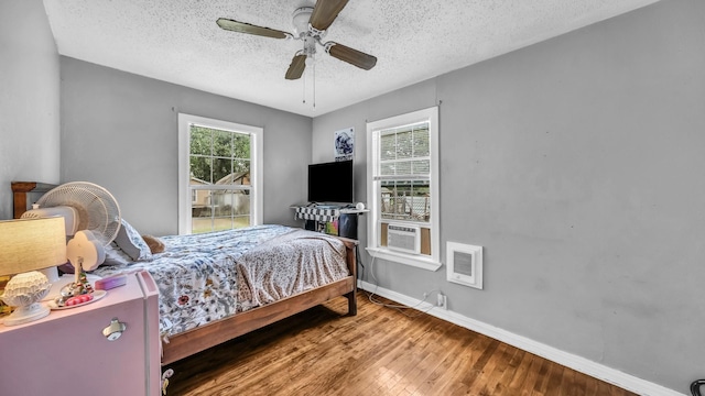 1007 SE 24th St, Mineral Wells, TX 76067 - bedroom featuring wood finished floors, baseboards, a textured ceiling, heating unit, and a ceiling fan