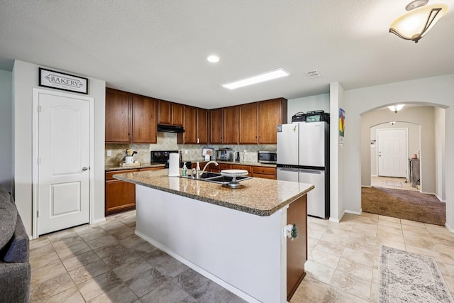 147 Cantle, Waxahachie, TX 75165 - kitchen featuring stainless steel appliances, arched walkways, decorative backsplash, a sink, and a kitchen island with sink