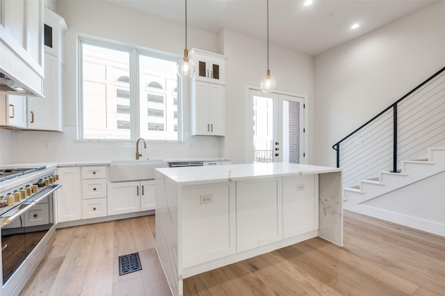 235 E Nash St Unit 124, Grapevine, TX 76051 - kitchen with range with two ovens, a sink, light wood-style floors, a kitchen island, and white cabinets