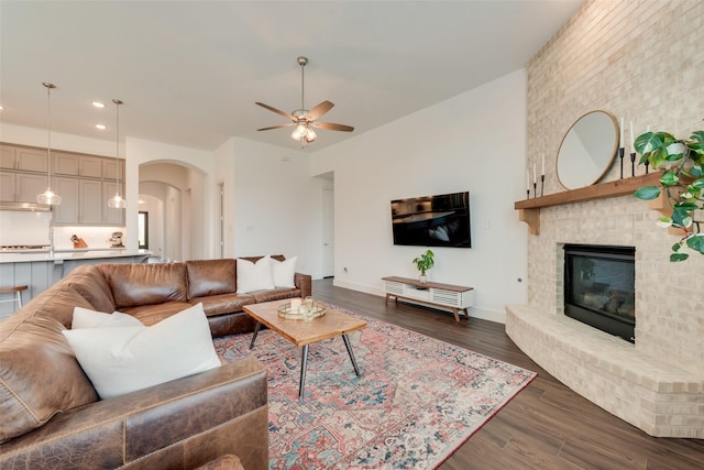 1124 Firecracker Dr, Justin, TX 76247 - living area with a ceiling fan, arched walkways, recessed lighting, dark wood-style flooring, and a brick fireplace