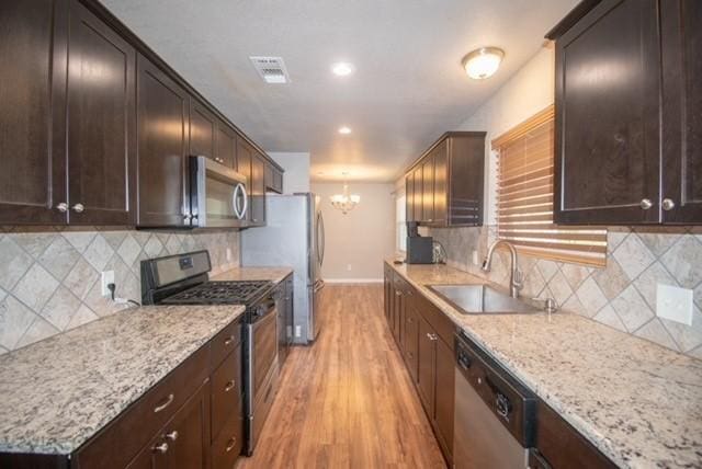 301 Patricia St, Lacy Lakeview, TX 76705 - kitchen featuring appliances with stainless steel finishes, a sink, a chandelier, light wood-style flooring, and baseboards