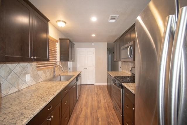 301 Patricia St, Lacy Lakeview, TX 76705 - kitchen featuring appliances with stainless steel finishes, light wood-style floors, baseboards, a sink, and dark brown cabinets