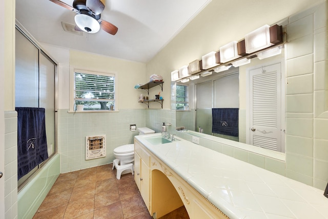 808 S Main St, Winnsboro, TX 75494 - full bathroom featuring heating unit, tile walls, ceiling fan, vanity, and toilet
