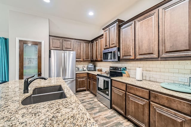 11741 Buckthorn Dr, Fort Worth, TX 76108 - kitchen with appliances with stainless steel finishes, a sink, light stone counters, tasteful backsplash, and light wood-style floors