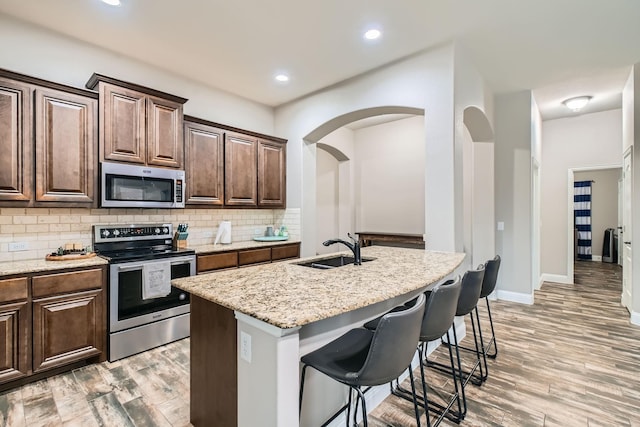 11741 Buckthorn Dr, Fort Worth, TX 76108 - kitchen with stainless steel appliances, a sink, a kitchen bar, decorative backsplash, and light stone countertops