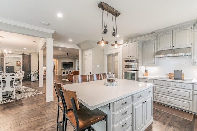 200 Sabine Creek Rd, Royse City, TX 75189 - kitchen with under cabinet range hood, black electric cooktop, stainless steel double oven, open floor plan, and decorative columns