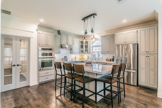 200 Sabine Creek Rd, Royse City, TX 75189 - kitchen featuring stainless steel appliances, under cabinet range hood, dark wood-type flooring, a breakfast bar area, and crown molding
