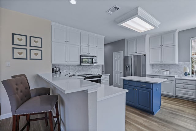 2904 Coventry Ln, Mckinney, TX 75069 - kitchen featuring appliances with stainless steel finishes, blue cabinets, a kitchen breakfast bar, light countertops, and decorative backsplash