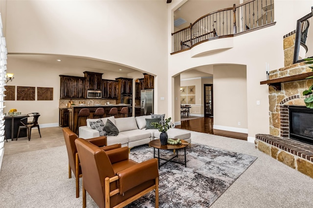 4312 Oxbow Dr, Mckinney, TX 75072 - living area featuring arched walkways, light colored carpet, a high ceiling, a stone fireplace, and baseboards