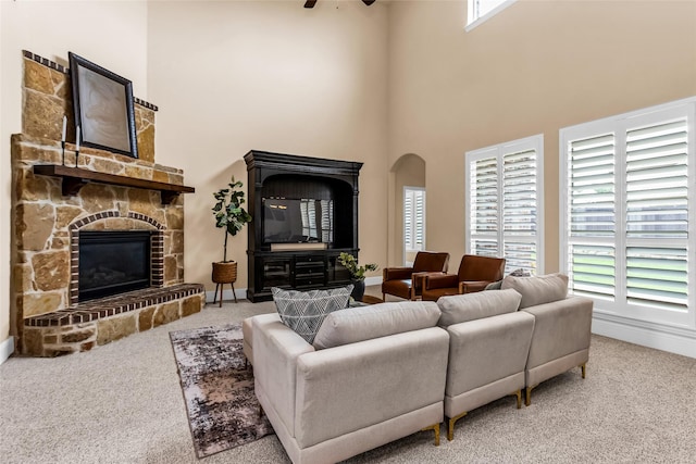 4312 Oxbow Dr, Mckinney, TX 75072 - carpeted living room with ceiling fan, a high ceiling, a stone fireplace, arched walkways, and baseboards