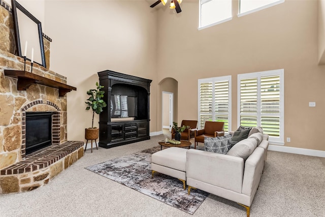 4312 Oxbow Dr, Mckinney, TX 75072 - carpeted living area with ceiling fan, a high ceiling, a stone fireplace, arched walkways, and baseboards