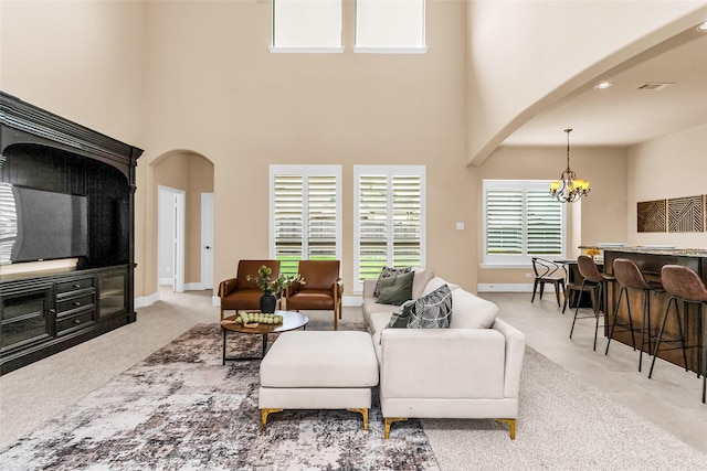 4312 Oxbow Dr, Mckinney, TX 75072 - living room with arched walkways, a high ceiling, a chandelier, and baseboards