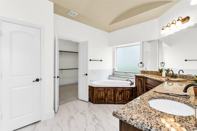 4312 Oxbow Dr, Mckinney, TX 75072 - bathroom featuring double vanity, marble look tiles, a garden tub, a spacious closet, and baseboards