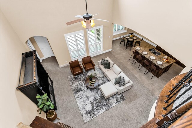 4312 Oxbow Dr, Mckinney, TX 75072 - living area featuring arched walkways, a towering ceiling, a ceiling fan, carpet floors, and baseboards