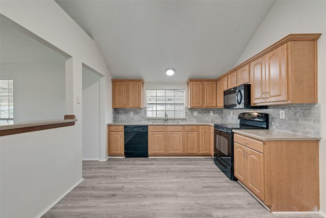 1326 Rosewood Ln, Lancaster, TX 75146 - kitchen featuring black appliances, vaulted ceiling, a sink, light countertops, and decorative backsplash