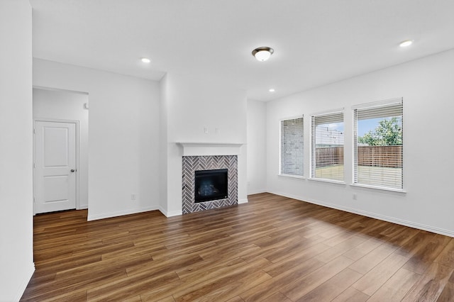 3804 Honeycomb Holw, Melissa, TX 75454 - unfurnished living room featuring wood finished floors, a tiled fireplace, baseboards, and recessed lighting