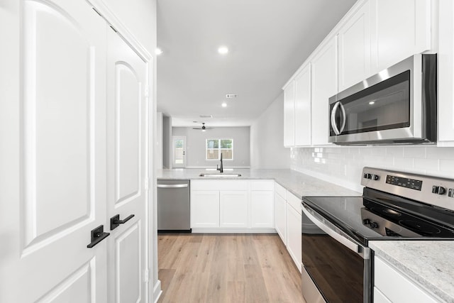 332 Live Oak Ln, Hutchins, TX 75141 - kitchen featuring stainless steel appliances, a sink, light wood-style floors, white cabinetry, and decorative backsplash