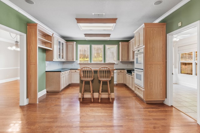504 Hilltop Pl, Joshua, TX 76058 - kitchen featuring double oven, dark countertops, ornamental molding, a breakfast bar area, and a kitchen island