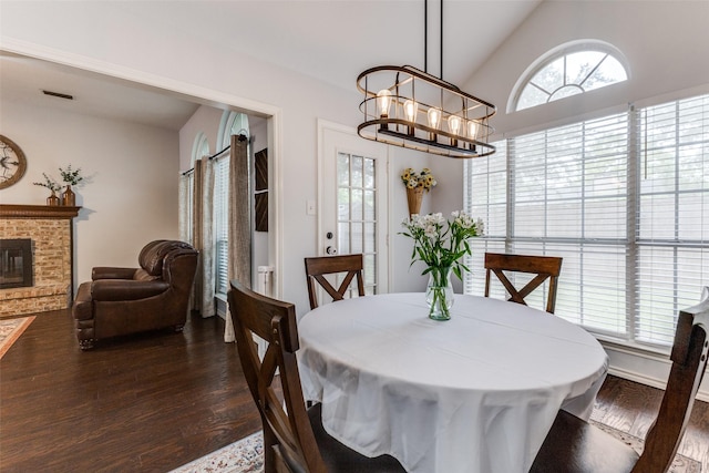 143 Westwood Dr, Rockwall, TX 75032 - dining room featuring dark wood-type flooring, a chandelier, lofted ceiling, and a brick fireplace