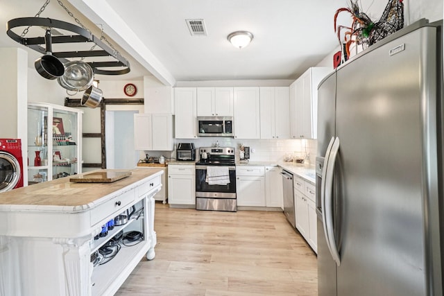 2704 Travis Ave, Fort Worth, TX 76110 - kitchen featuring stainless steel appliances, light wood-style flooring, white cabinets, decorative backsplash, and a kitchen island