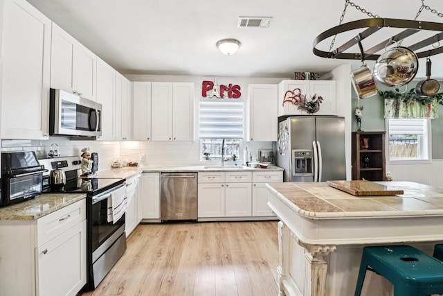 2704 Travis Ave, Fort Worth, TX 76110 - kitchen featuring appliances with stainless steel finishes, a sink, plenty of natural light, and light wood-style flooring