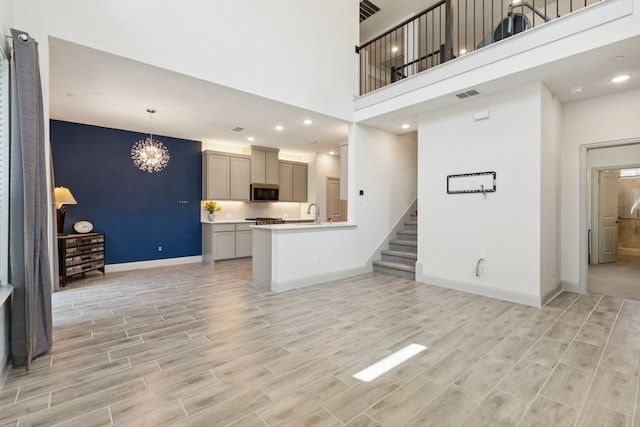 984 Mikaela Dr, Allen, TX 75013 - unfurnished living room with baseboards, a high ceiling, stairway, light wood-type flooring, and a chandelier
