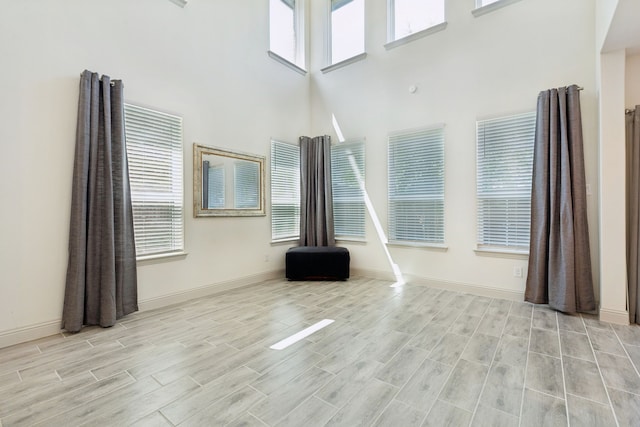 984 Mikaela Dr, Allen, TX 75013 - unfurnished living room with a high ceiling, healthy amount of natural light, wood tiled floors, and baseboards