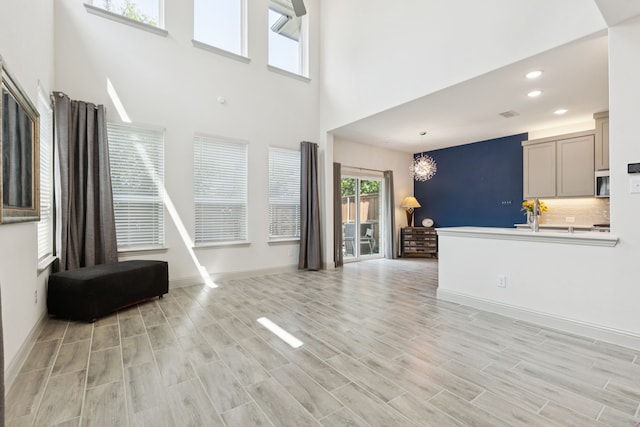 984 Mikaela Dr, Allen, TX 75013 - unfurnished living room featuring a chandelier, a high ceiling, recessed lighting, light wood finished floors, and baseboards