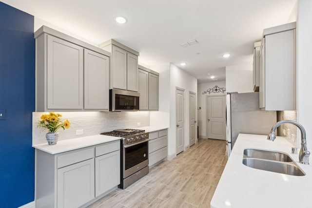 984 Mikaela Dr, Allen, TX 75013 - kitchen with stainless steel appliances, a sink, gray cabinets, tasteful backsplash, and light countertops