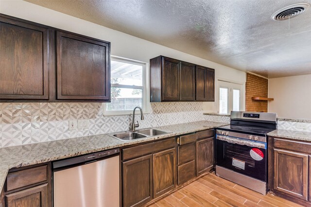 4704 S Drive, Fort Worth, TX 76109 - kitchen with appliances with stainless steel finishes, a sink, light wood-type flooring, plenty of natural light, and a textured ceiling