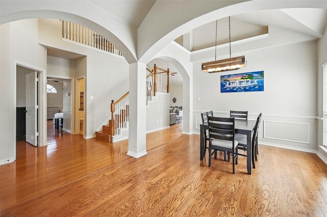 315 Hudson Falls Dr, Arlington, TX 76002 - dining area featuring stairway, arched walkways, light wood-style flooring, a chandelier, and a towering ceiling