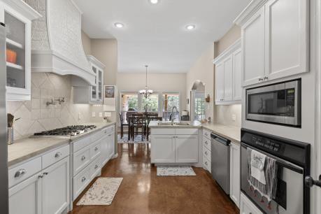 240 Lakeside Oaks Cir, Lakeside, TX 76135 - kitchen with stainless steel appliances, a sink, a peninsula, custom range hood, and tasteful backsplash