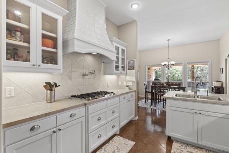 240 Lakeside Oaks Cir, Lakeside, TX 76135 - kitchen featuring stainless steel gas stovetop, premium range hood, a sink, a chandelier, and decorative backsplash