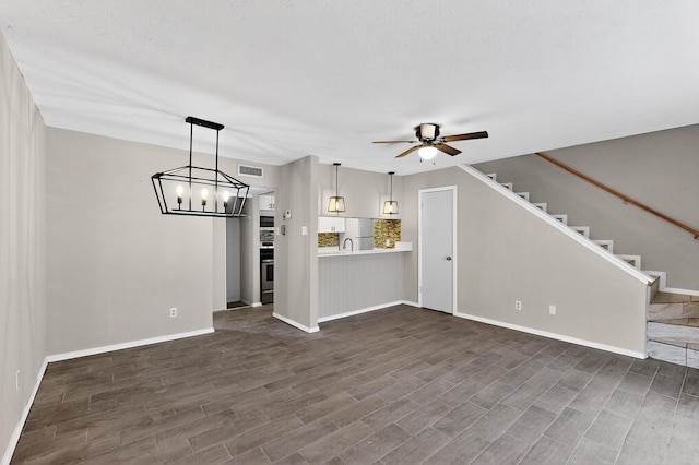 2627 Douglas Ave Unit 130, Dallas, TX 75219 - unfurnished living room with a ceiling fan, dark wood-style flooring, baseboards, and a chandelier
