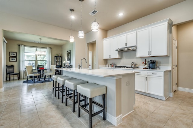 9513 Windwood Ln, Denton, TX 76207 - kitchen featuring a center island with sink, light countertops, under cabinet range hood, a sink, and white cabinetry