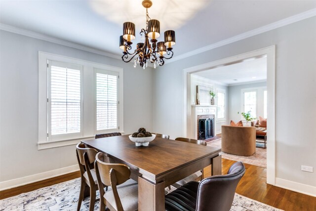 3913 Modlin Ave, Fort Worth, TX 76107 - dining space with a fireplace with raised hearth, baseboards, ornamental molding, a chandelier, and wood finished floors
