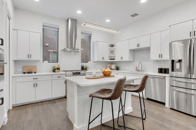1920 Dowgate Ct, Dallas, TX 75204 - kitchen with appliances with stainless steel finishes, wall chimney range hood, a breakfast bar area, tasteful backsplash, and light wood-type flooring
