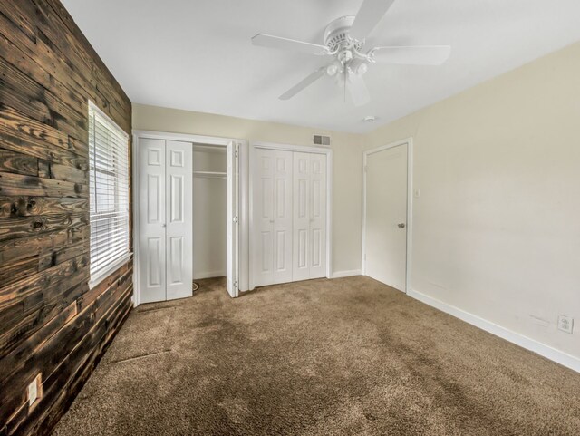 13439 Challaburton, Farmers Branch, TX 75234 - unfurnished bedroom with two closets, carpet flooring, baseboards, a ceiling fan, and wood walls