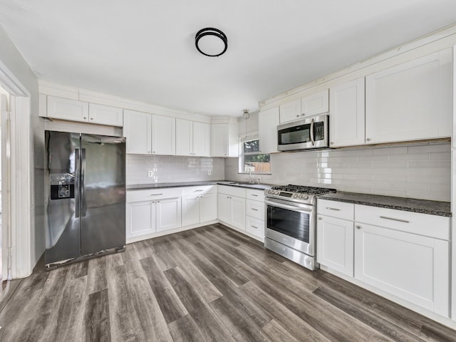 13439 Challaburton, Farmers Branch, TX 75234 - kitchen with appliances with stainless steel finishes, a sink, dark countertops, decorative backsplash, and white cabinetry