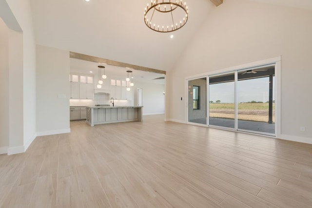 160 Maci Dr, Waxahachie, TX 75167 - unfurnished living room featuring high vaulted ceiling, a chandelier, baseboards, a sink, and light wood-style flooring