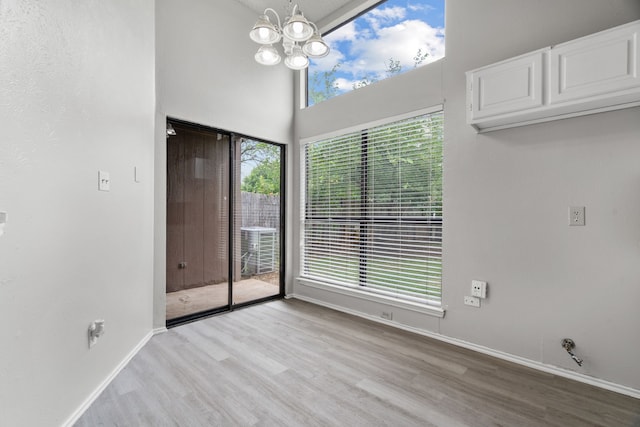 2526 Butterfield Dr, Fort Worth, TX 76133 - unfurnished dining area featuring light wood-style flooring, a chandelier, baseboards, and a high ceiling