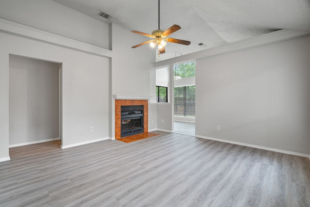 2526 Butterfield Dr, Fort Worth, TX 76133 - unfurnished living room with a textured ceiling, ceiling fan, wood finished floors, a tiled fireplace, and high vaulted ceiling