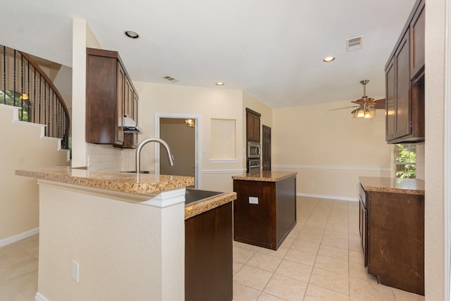 3010 Partridge Ln, Mckinney, TX 75072 - kitchen featuring a kitchen island, a ceiling fan, dark brown cabinets, stainless steel microwave, and recessed lighting