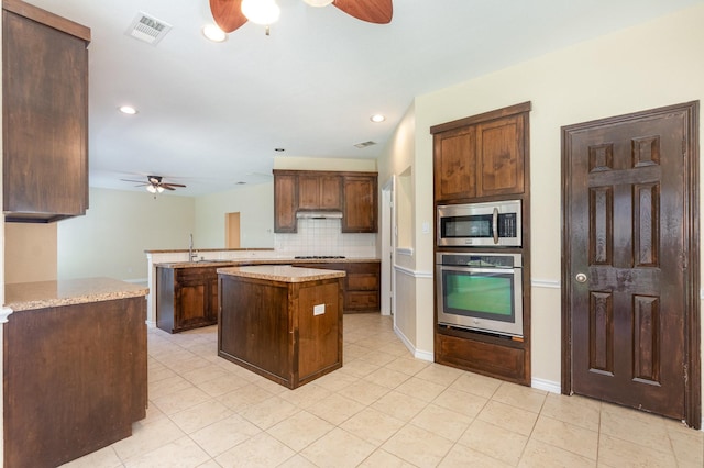 3010 Partridge Ln, Mckinney, TX 75072 - kitchen with ceiling fan, appliances with stainless steel finishes, tasteful backsplash, a kitchen island, and light tile patterned flooring