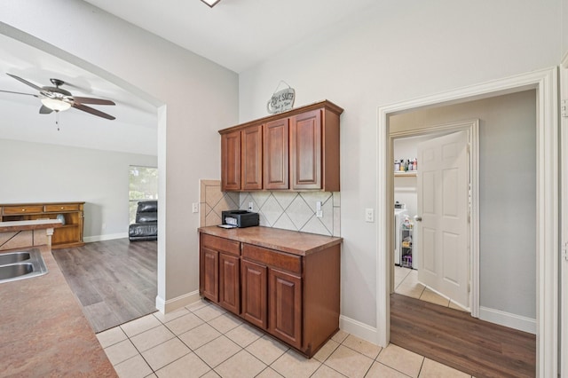 711 Mason Ln, Waxahachie, TX 75167 - kitchen with a ceiling fan, decorative backsplash, light tile patterned floors, baseboards, and brown cabinetry