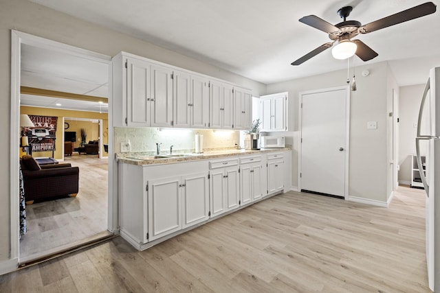 1407 S Alamo Rd, Rockwall, TX 75087 - kitchen featuring white microwave, light wood-style flooring, a ceiling fan, and white cabinetry