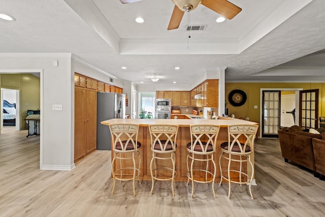 1407 S Alamo Rd, Rockwall, TX 75087 - kitchen featuring appliances with stainless steel finishes, light wood-style flooring, a peninsula, a tray ceiling, and crown molding