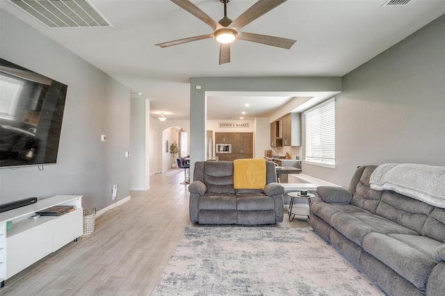 1112 Goldenrod Dr, Godley, TX 76044 - living area with arched walkways, a ceiling fan, light wood finished floors, and baseboards