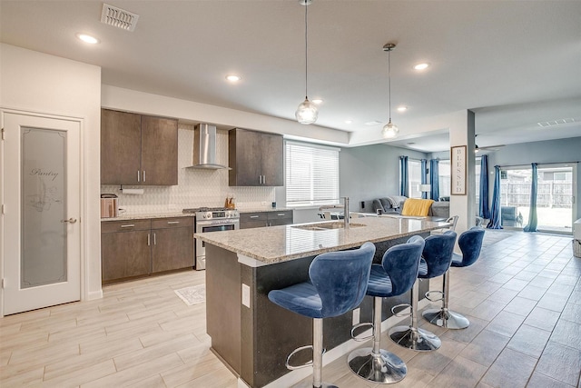 1112 Goldenrod Dr, Godley, TX 76044 - kitchen featuring gas stove, wall chimney range hood, a sink, open floor plan, and healthy amount of natural light
