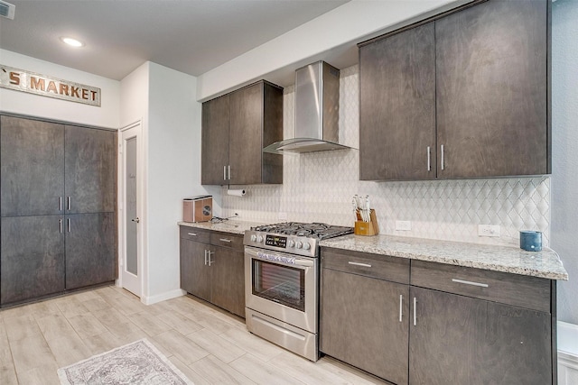 1112 Goldenrod Dr, Godley, TX 76044 - kitchen featuring stainless steel gas range, wall chimney exhaust hood, dark brown cabinetry, decorative backsplash, and recessed lighting